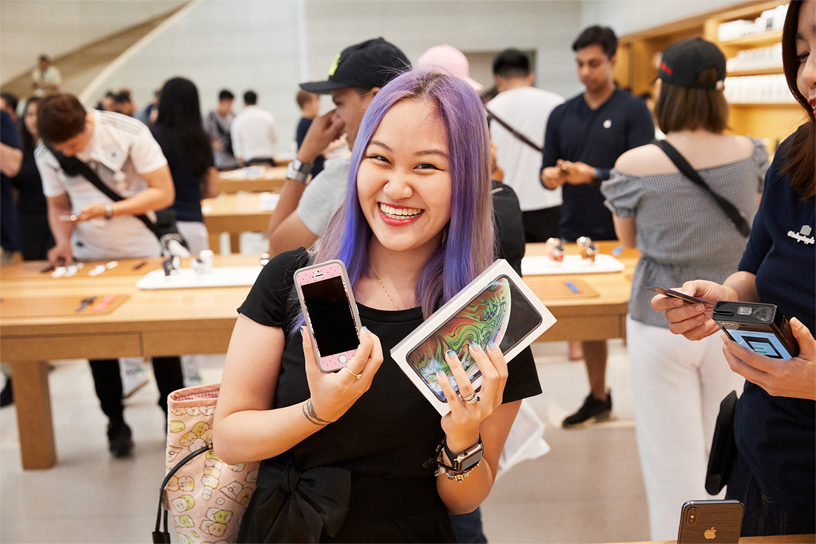 一位年轻的女士正在用旧 iPhone 升级换购新款 iPhone Xs Max。