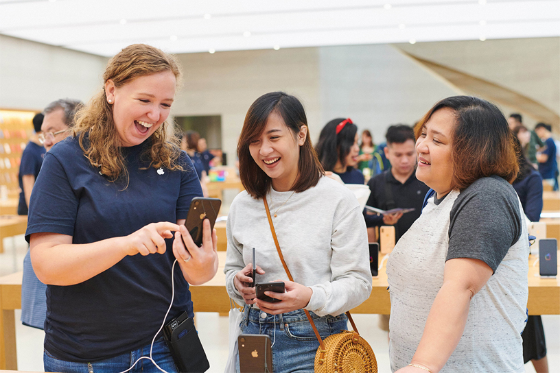 Apple 零售店店员将 iPhone Xr 包装盒交给顾客。