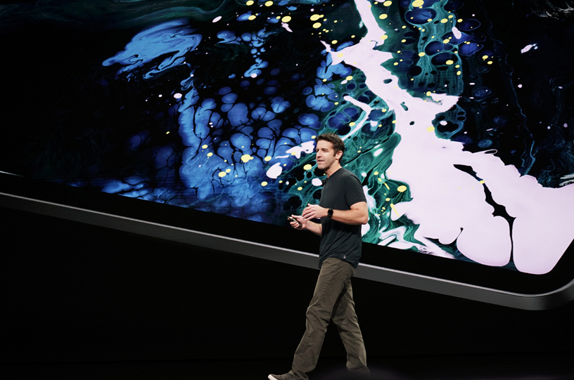 John Ternus 站在舞台上，身后正在演示 iPad Pro 图片。
