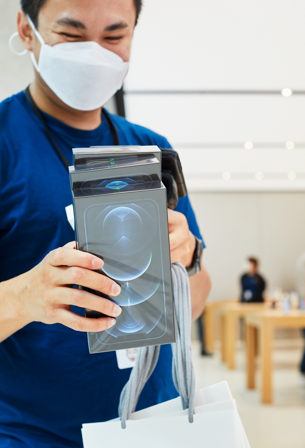 一位 Apple Sydney 零售店团队成员正在扫描 iPhone 12 Pro Max 的包装。