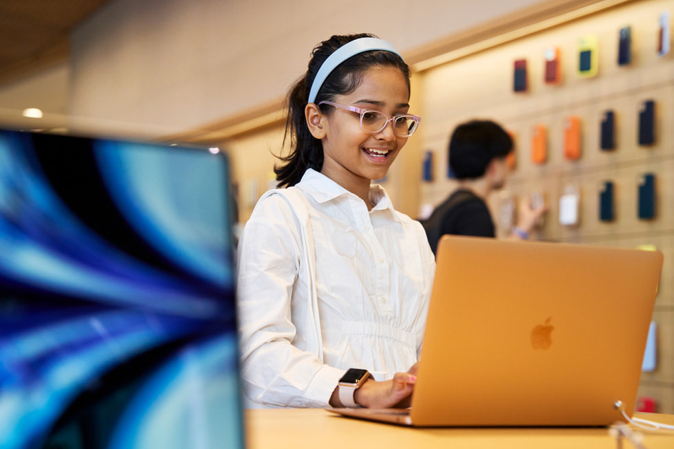 一位年轻的顾客在 Apple BKC 零售店内使用 MacBook Air。
