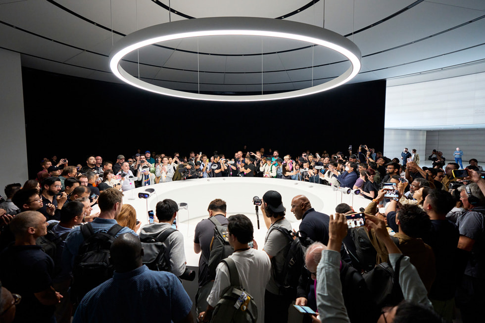 在 Apple Park，媒体人员围绕在 Apple Vision Pro 展示桌旁。