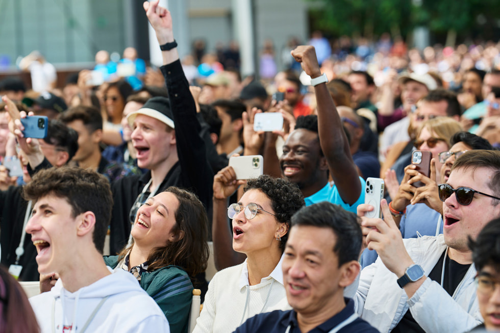 开发者们在 Apple Park 户外场地欢呼并举起 iPhone 的特写照片。