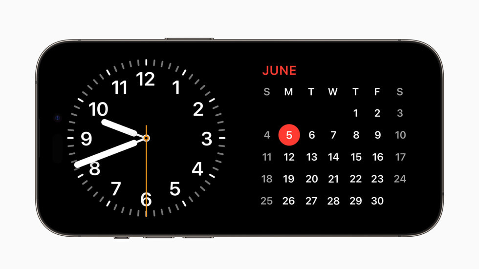 在运行 iOS 17 的 iPhone 14 Pro 上，StandBy 正在显示一个时钟和日历视图。