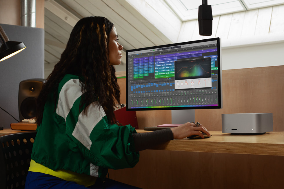图示为侧面对着镜头的一位 Apple 用户正在使用搭载 M2 Ultra 芯片的 Mac Studio。