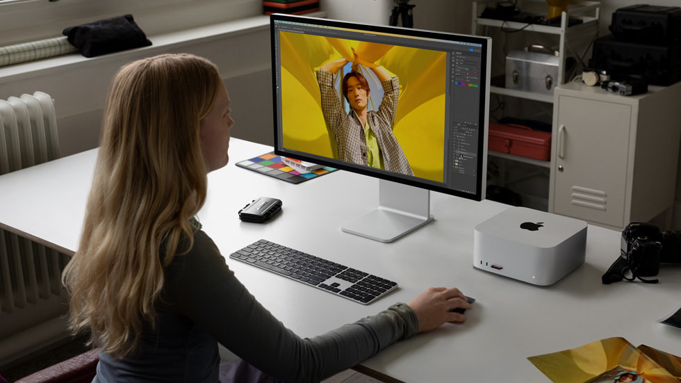 一个人坐在工作站内，正在使用 Mac Studio 和 Mac Pro。