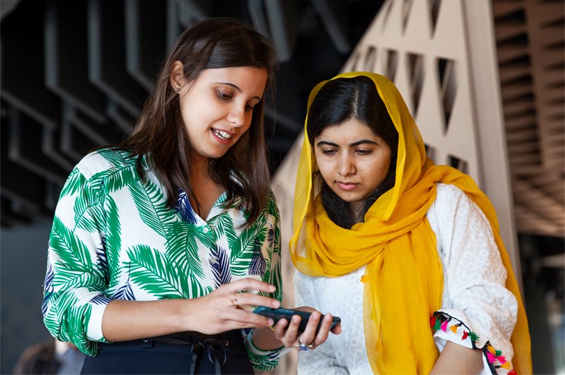 Malala Yousafzai 在里约 Apple 开发者学院与一名女士一同看着一部 iPhone。