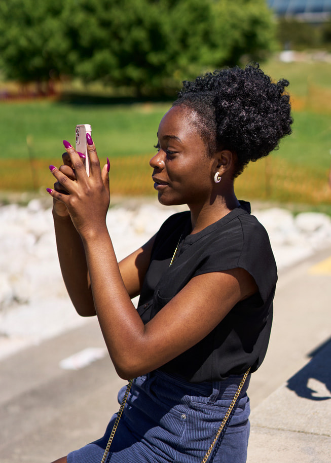 Adetokunbo Opeifa 在公园中举起 iPhone 拍摄照片。