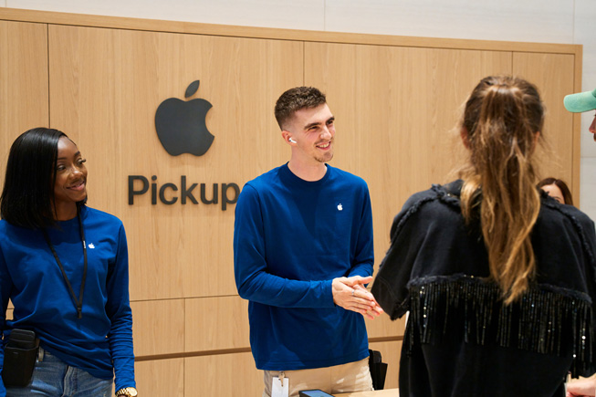Apple 团队成员在 Apple Store 零售店的 Apple Pickup 区域协助顾客自取订购的产品。