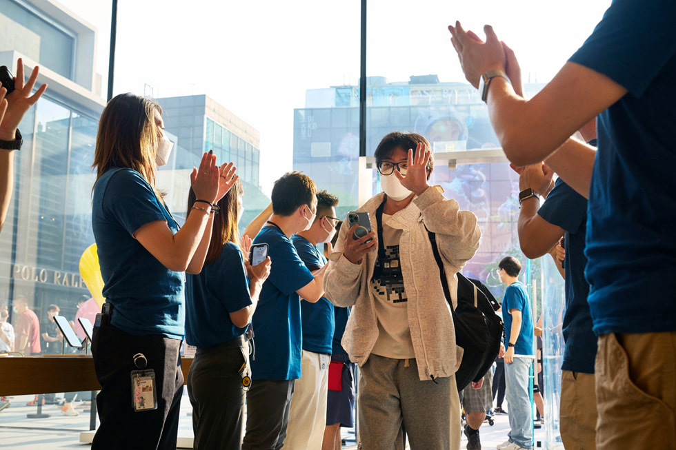 Apple 三里屯零售店团队成员鼓掌欢迎顾客进店。