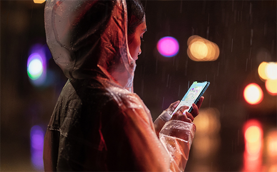 女子在雨中手握 iPhone XR。