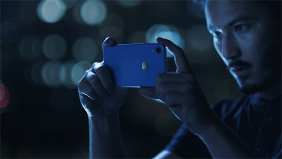 一位男士使用蓝色 iPhone XR 在夜间拍照。