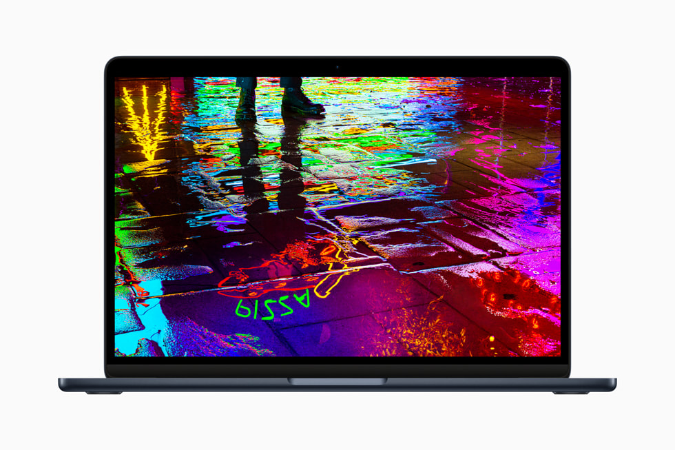 搭载 M2 芯片的全新 MacBook Air 屏幕上显示一幅图片：湿漉漉的街道地面上反射着霓虹灯。 