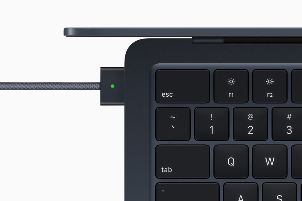 MagSafe 电源适配器连接午夜色 MacBook Air 的特写。