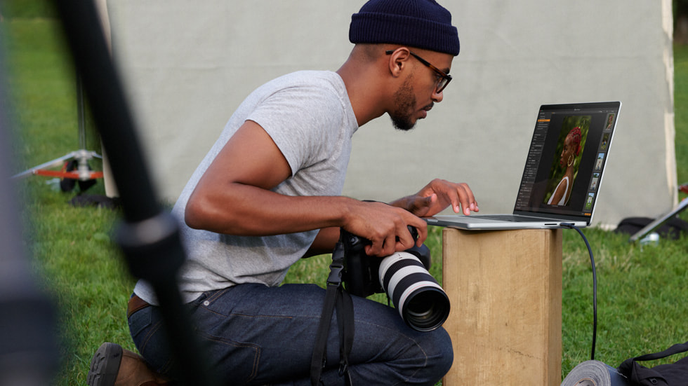 一名摄影师在户外现场使用 MacBook Pro 编辑照片。