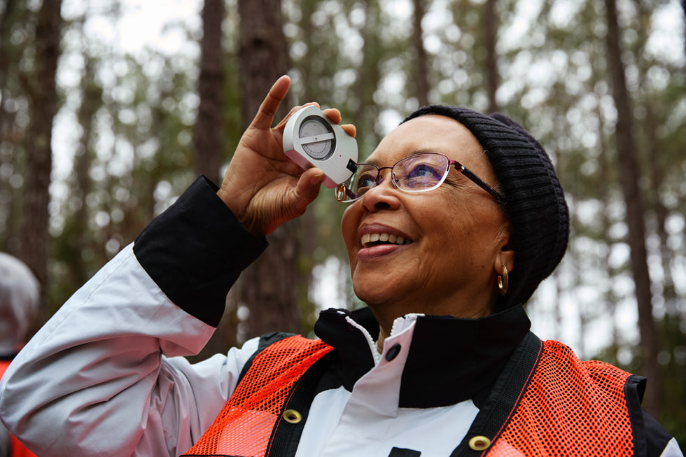 在社区森林里，一位女性将测量设备举到眼前。