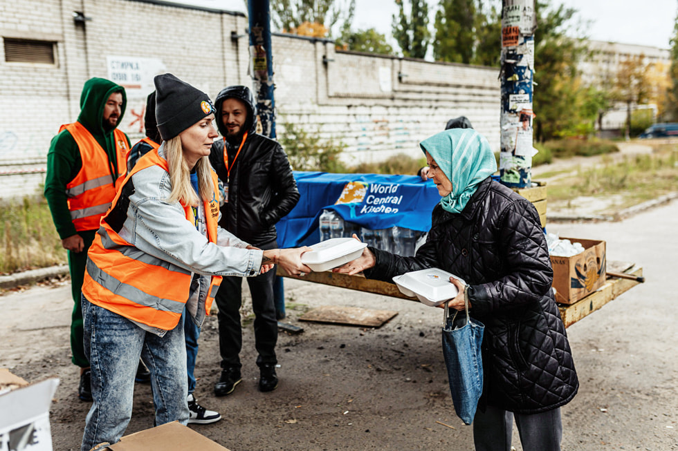 一位 Apple 团队成员在乌克兰参与世界中央厨房的志愿工作，向那里的人们发放食物。