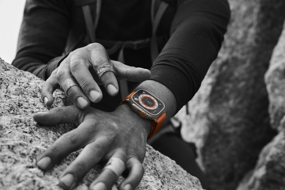 特写照片：一双缠着胶带的手放在岩石上，其中一只手腕佩戴着 Apple Watch Ultra。