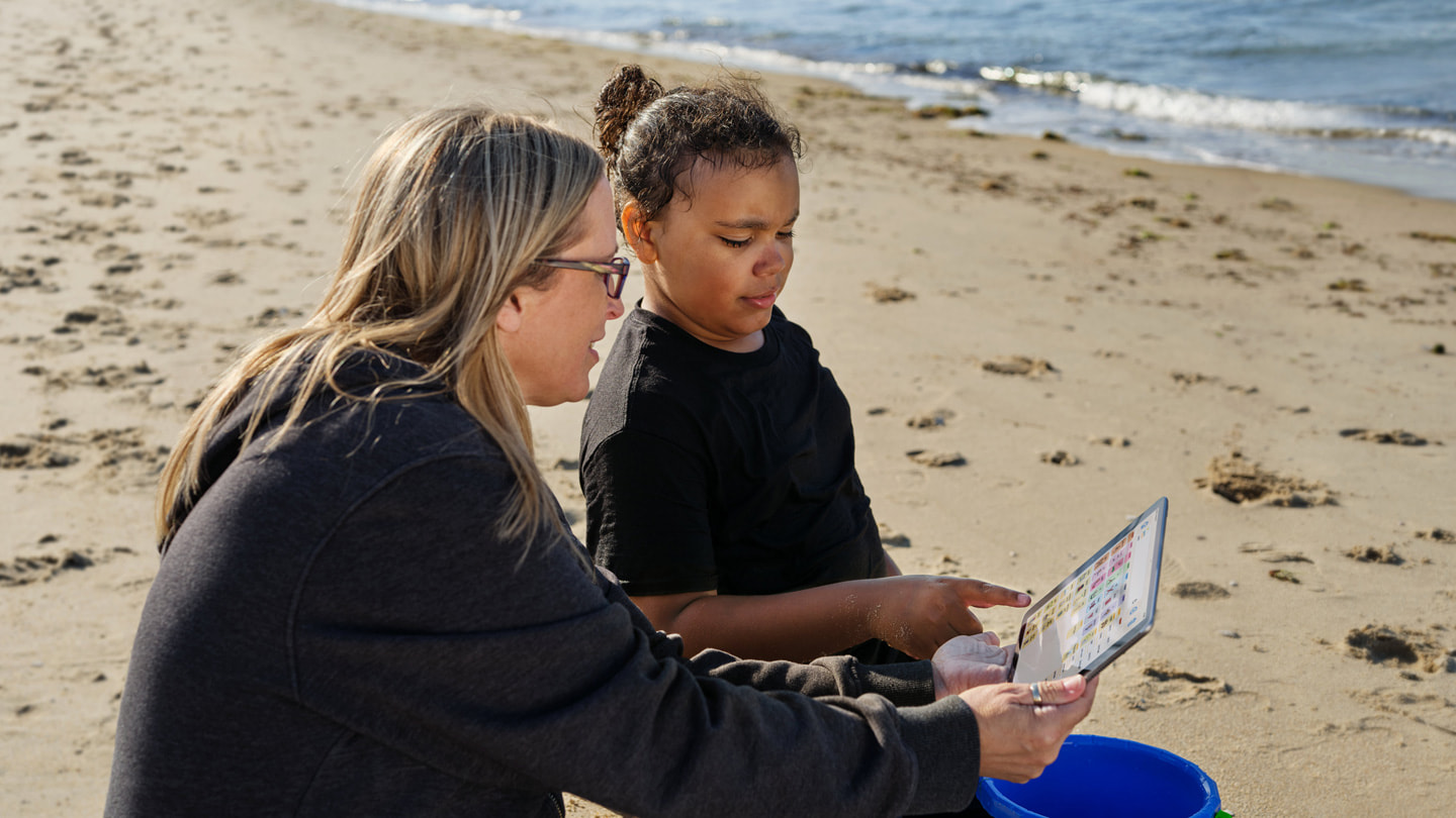 在弗吉尼亚海滩，Jay Ashburn（右）在母亲的 iPad 上使用 Proloquo 与她交流。