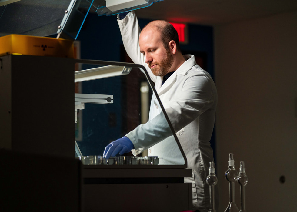 一名穿着实验室外套和手套的男人在实验室环境中使用机器。
