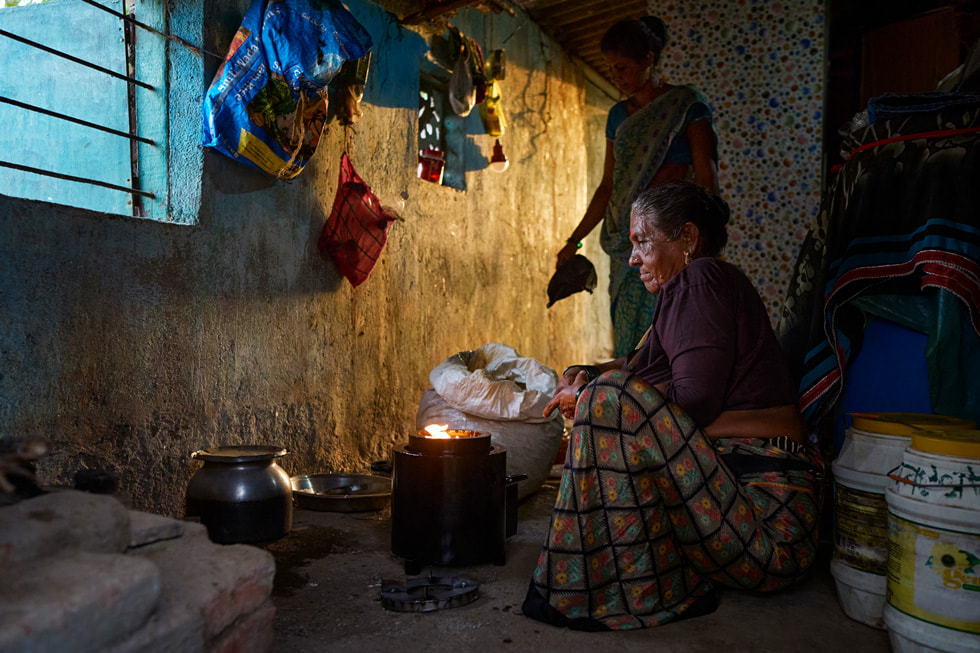 两位印度女性使用便携式生物质炉具做饭。