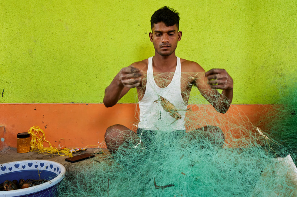 在印度马哈拉施特拉邦 Raigad 县，一位渔民正在检查渔网。