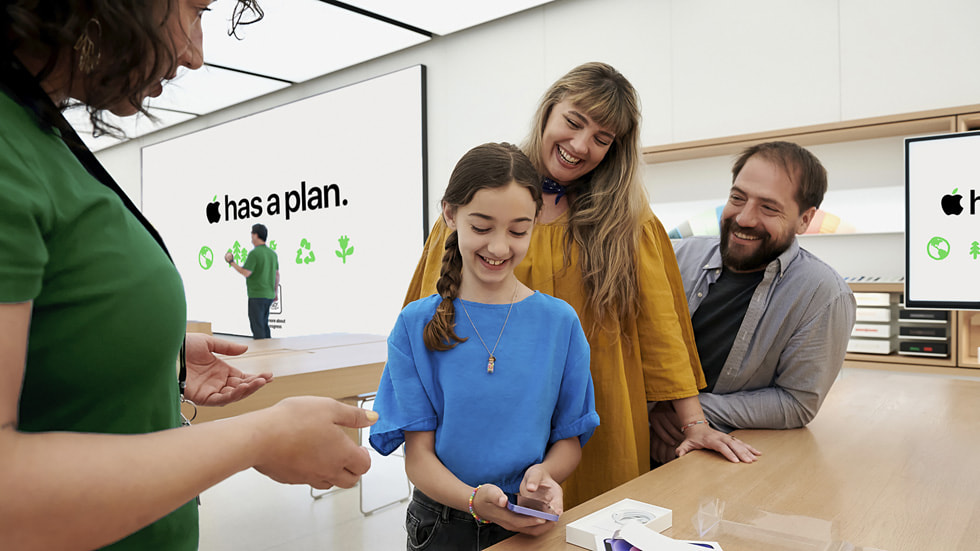 两位成年顾客和一位小朋友在 Apple Store 与店内团队成员交谈。