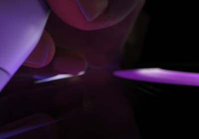 用户手握 Apple Pencil Pro，做出书写姿势。笔尖向下按向屏幕时，屏幕显示较粗的亮紫色笔触被绘制出来。