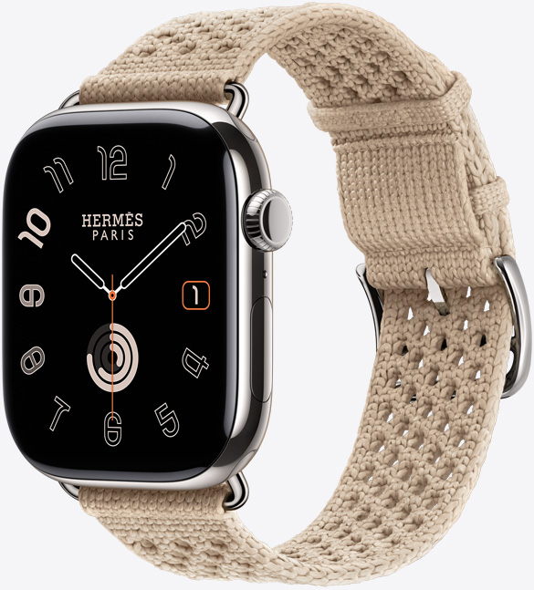 Apple Watch Hermès Series 11，展示银色钛金属表壳及其抛光外观、全面屏和圆角设计、右侧外观、数码表冠、麦克风、侧边按钮、模拟表盘 (时针、分针、秒针)，以及搭配的 Argile 黏土色 (米色系) Néo Tricot 表带，表带采用针织聚酰胺纱线材质，中央具有调节孔，配有银色表扣和五金件。