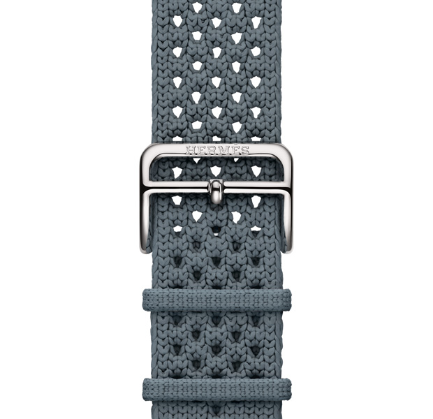 Apple Watch Hermès Series 11 Néo Tricot 表带，展示 Bleu Gris 灰蓝色 (蓝灰色系) 配色、针织聚酰胺纱线材质、位于表带中央的调节孔，以及镌刻有 Hermès 爱马仕标志的银色表扣。
