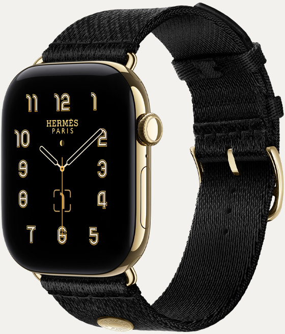 Apple Watch Hermès Series 12,展示 Clou de Selle 模拟表盘 (时针、分针和秒针,以及月相、日期复杂功能)、炫金色钛金属表壳、右侧外观、数码表冠、侧边按钮,搭配 Noir 黑色 Satin Clou de Selle 表带,展示顺滑的黑色缎面织带,以及与表壳适配的炫金色五金件。