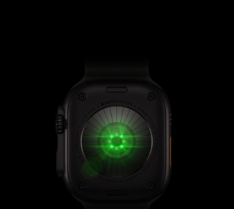 Apple Watch Ultra 4 的背面，展示黑色钛金属表壳、亮着绿色 LED 灯光的多个圆形传感器，以及左侧外观、数码表冠和凸起的侧边按钮。