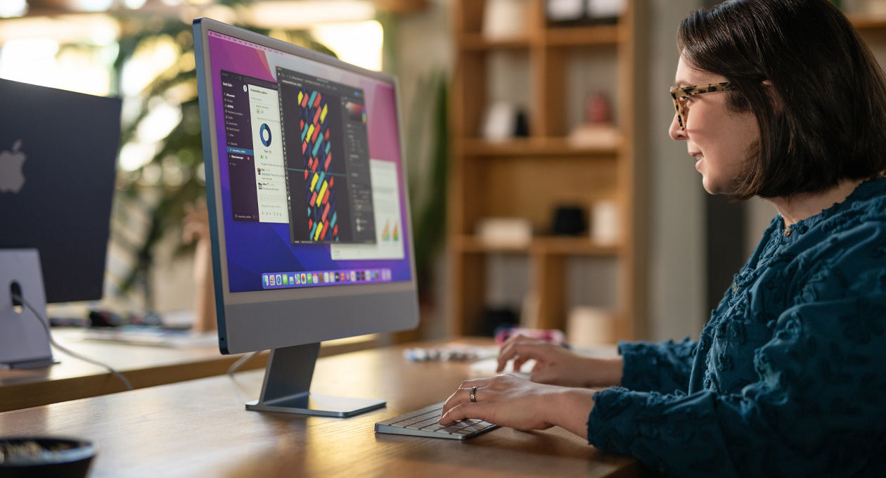 一人在办公环境中使用 iMac，屏幕显示一款多彩的设计 app