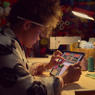 一个人坐在桌前，使用双指在 iPad 的屏幕上放大图像。