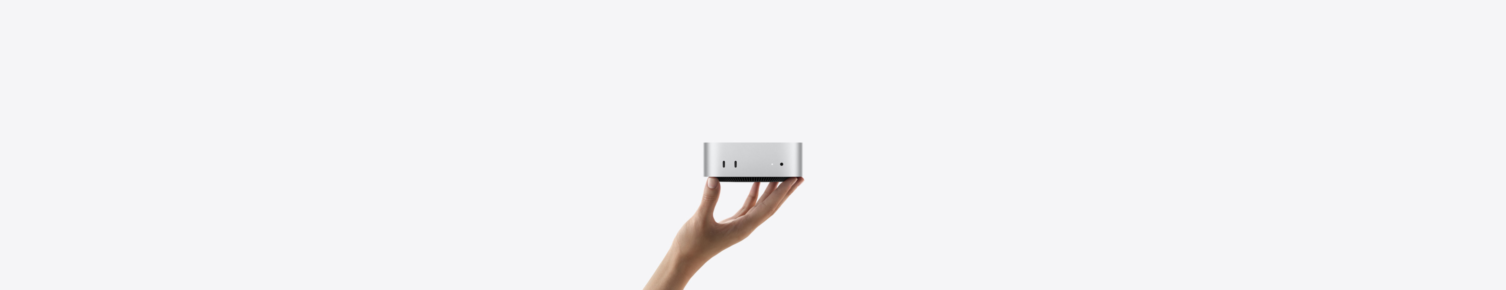 银色 Mac mini 正面视图，设备平稳地放置在向上伸出的手掌指尖上，展示两个雷雳端口、状态指示灯、耳机插孔，以及底部收窄的黑色底座、平坦的顶部、圆润侧边和直边设计。