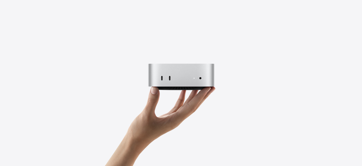 银色 Mac mini 正面视图，设备平稳地放置在向上伸出的手掌指尖上，展示两个雷雳端口、状态指示灯、耳机插孔，以及底部收窄的黑色底座、平坦的顶部、圆润侧边和直边设计。