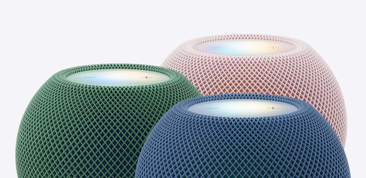 绿色、蓝色和粉色三部 HomePod mini 2 扬声器的顶部外观特写，展示声学网面织物和发光的触控面板。