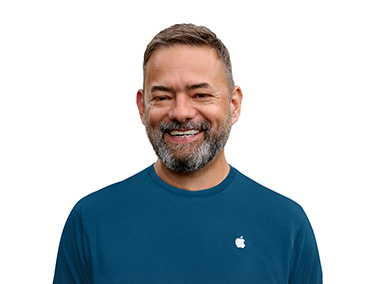 一位 Apple Specialist 专家身穿一侧带有 Apple 标志的蓝色上衣，面带微笑。