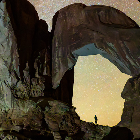一张星空下的峡谷照片，峡谷中站着一个人。