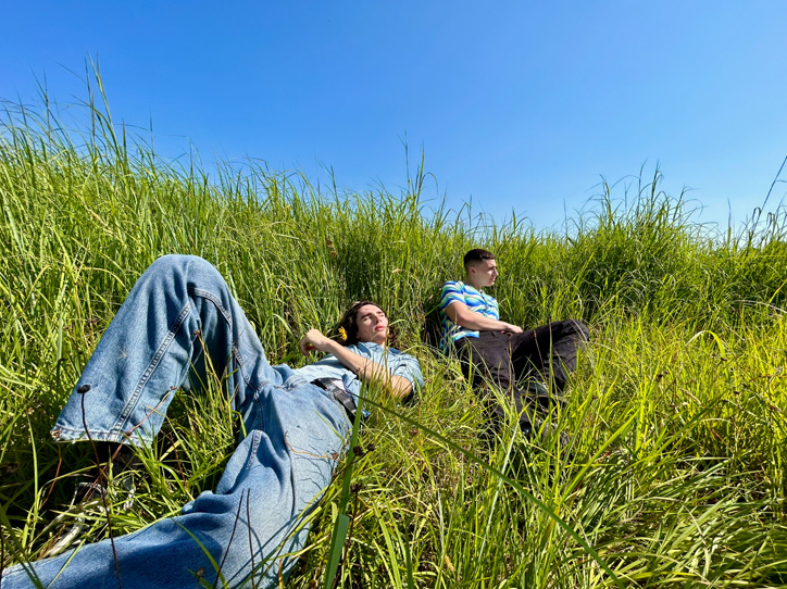 超广角摄像头拍摄的照片，两个小伙子躺在草地上。