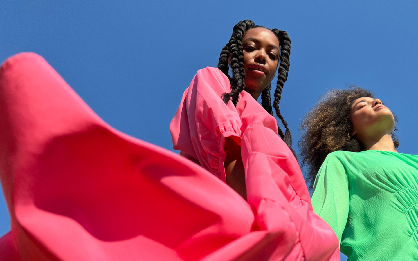 阳光下身穿亮粉色裙装的人像照，以 Pro 水准主摄拍摄。