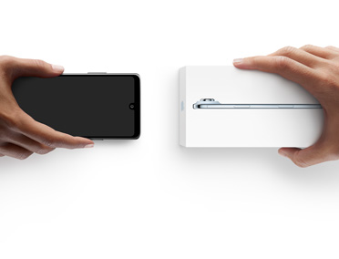 左边一只手拿着一部用于折抵的其他智能手机，换取右边另一只手中未拆包装的全新 iPhone Air。