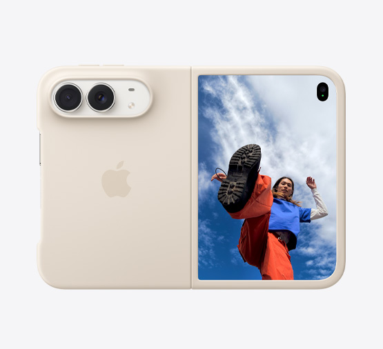 装有沙砾色硅胶保护壳的星光白色 iPhone Duo，横向完全展开，融合式双摄系统位于机身左上角，保护壳覆盖机身背面和正面显示屏外边缘，右侧的外屏显示人物站在蓝天白云之下的图像。