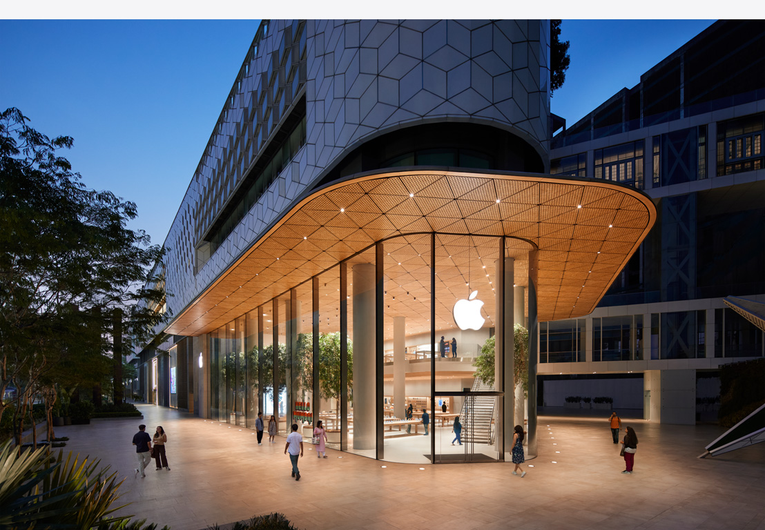 夜幕下的 Apple Store 零售店，巨大的玻璃窗透出店内的灯光，正门上方装有 Apple 标志。