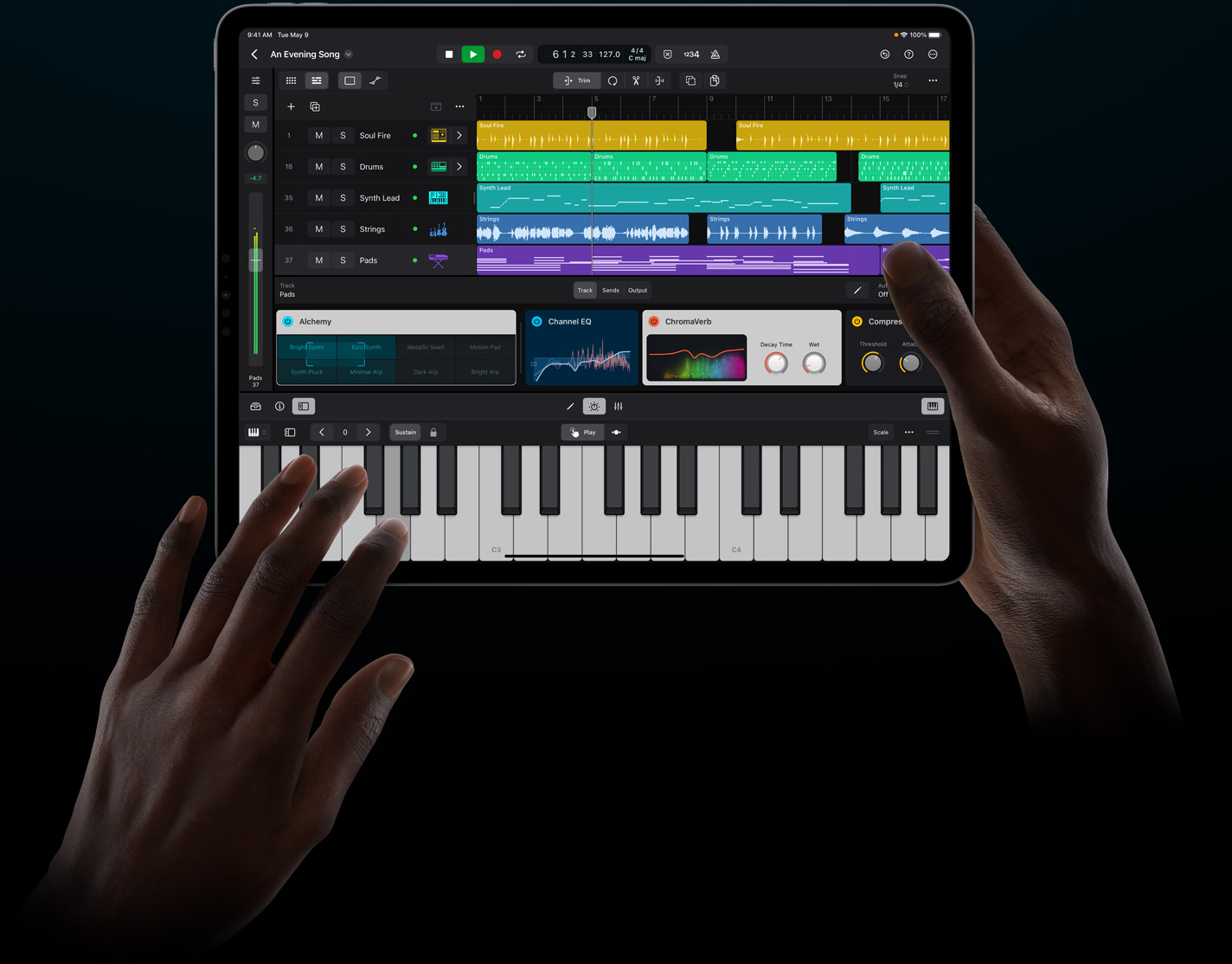 一双手拿着一部 iPad Pro，以触控方式在 iPad 版 Logic Pro 中演奏虚拟乐器。