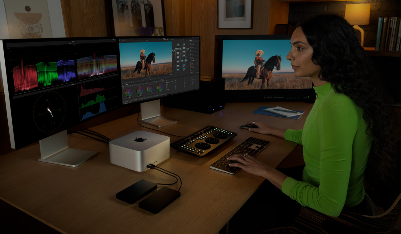 一位专业人士使用 Mac Studio 进行文件编辑，电脑外接有三台显示器。