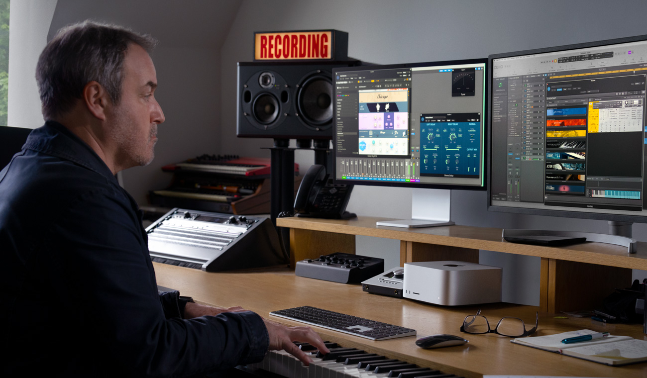 一位音乐人用钢琴在配有 Studio Display 的 Mac Studio 上创作音频混音。