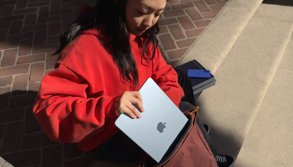 一位学生将 MacBook Air 放入背包中