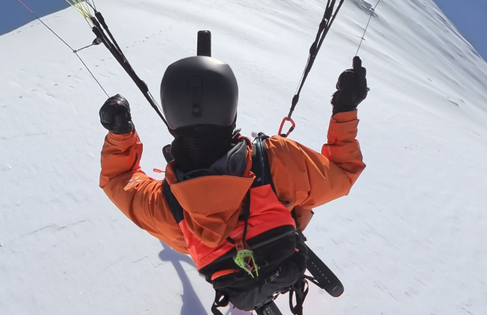 广角视频画面中滑翔伞滑雪者在空中穿越连绵的山脊。