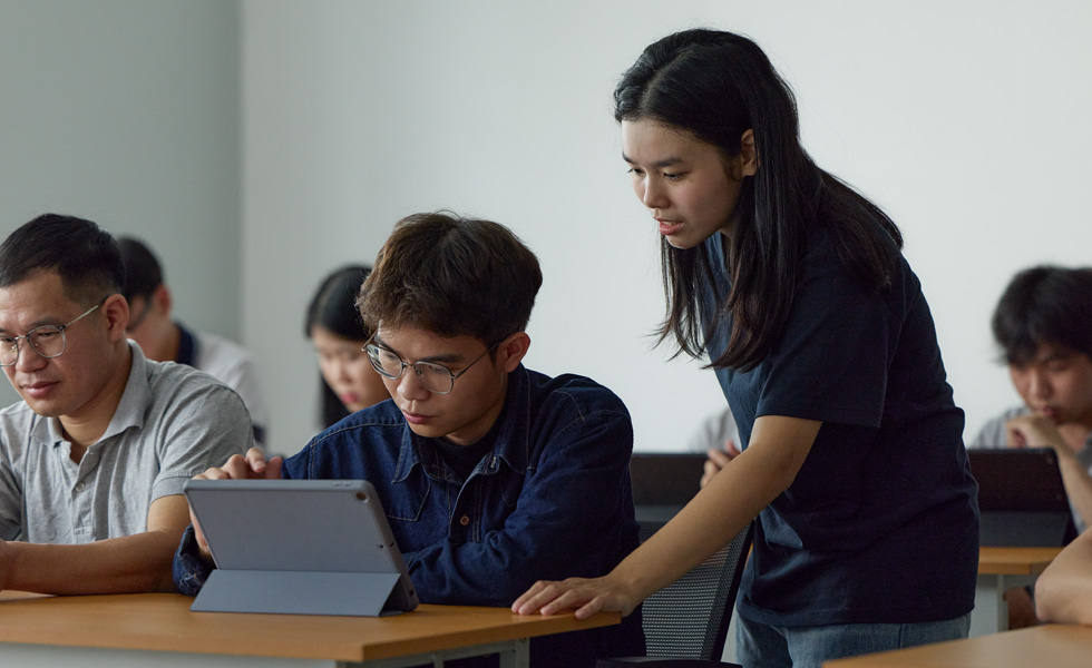 两个人在课堂环境中使用 Apple 平板电脑开展协作